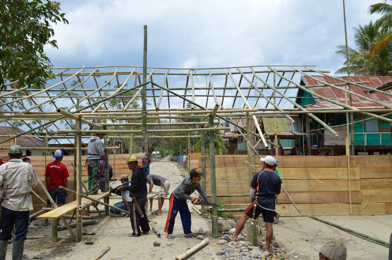 A team of adults constructing a bamboo structure in South Sulawesi, Indonesia, showcasing teamwork and local craftsmanship.